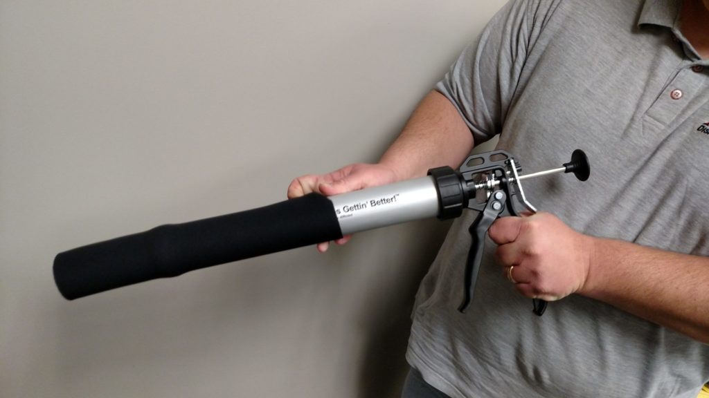 Man applying Albion insultating barrel sleeve to caulk gun